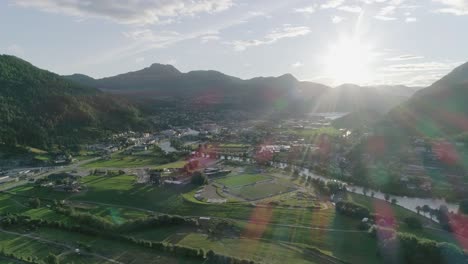 Aerial-Slomo-Wide-shot-of-a-Norwegian-Town-during-Sunset,-Blue-sky,-with-a-nice-Lens-Flare