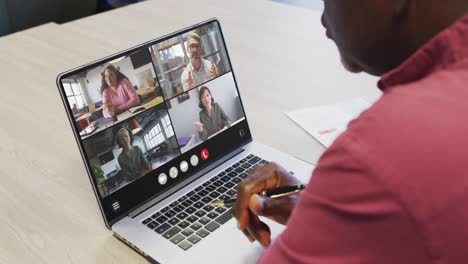 african american man using laptop for video call, with diverse business colleagues on screen