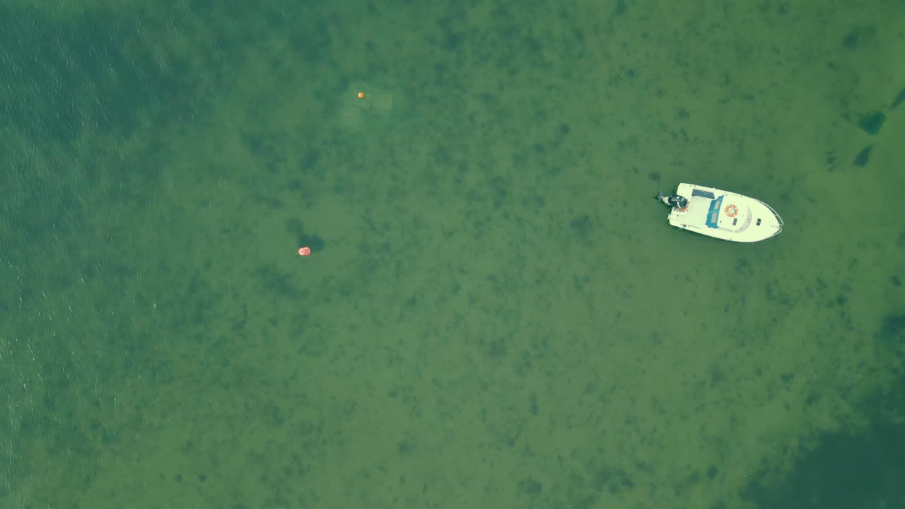 Top down aerial small white boat on right side, slow motion