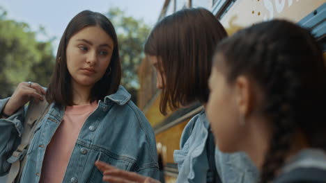 cute school girl telling funny story to friends close up. pupil stand at bus.