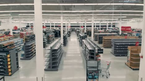 aerial view of a spacious, partially stocked retail store with visible aisles and shelves, indicating a shopping environment that is undergoing reorganization or inventory changes