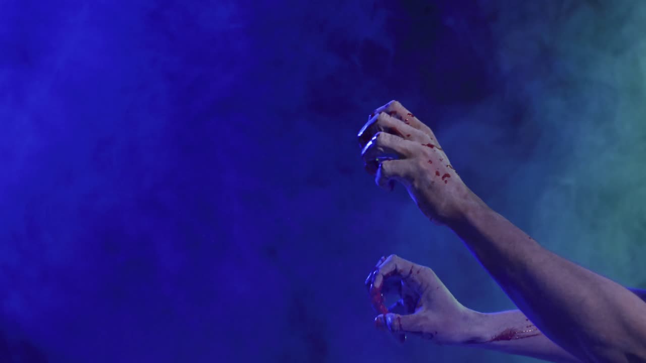Video of hands covered with blood moving over smoke on black background