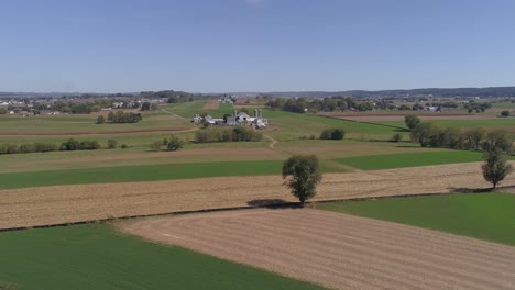 Luftaufnahme-Der-Amischen-Landschaft-Des-Landwirtschaftlichen-Arbeitsfeldes-An-Einer-Eisenbahnstrecke,-Während-Sich-Eine-Dampfmaschine-Nähert,-Wie-Sie-Von-Einer-Drohne-Gesehen-Wird