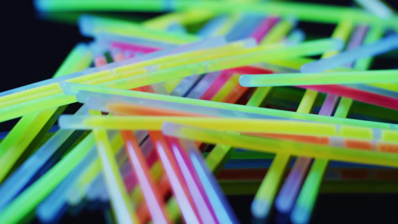 animación de múltiples palos de brillo de neón coloridos sobre un fondo negro