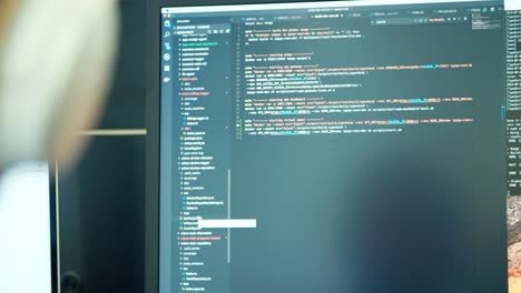 programador de computadora sentado frente a una pantalla codificando software