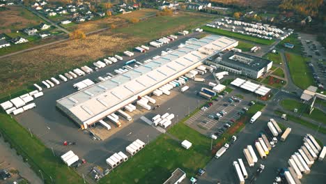 Warehouses,-huge-logistics-center-near-the-highway,-view-of-a-large-number-of-cargo-trailers-and-containers,-international-cargo-transportation,-aerial-view