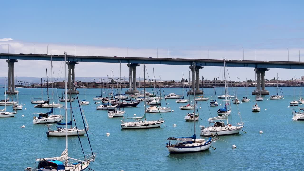 Low flying aerial view of sailboats Mooring in San Diego Bay with Coronado Bridge in the background