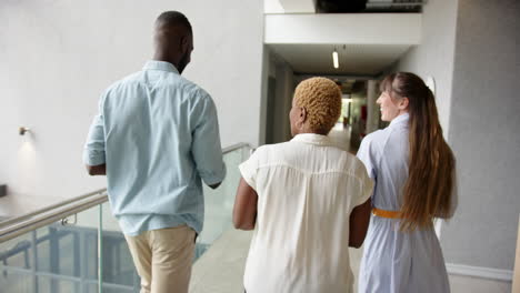 walking in hallway, diverse colleagues discussing work in modern office building
