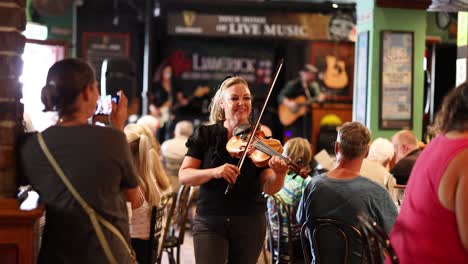 musician playing violin for an engaged pub audience