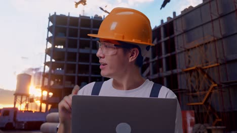trabajador asiático usando una computadora portátil y apuntando hacia un lado en el sitio de construcción