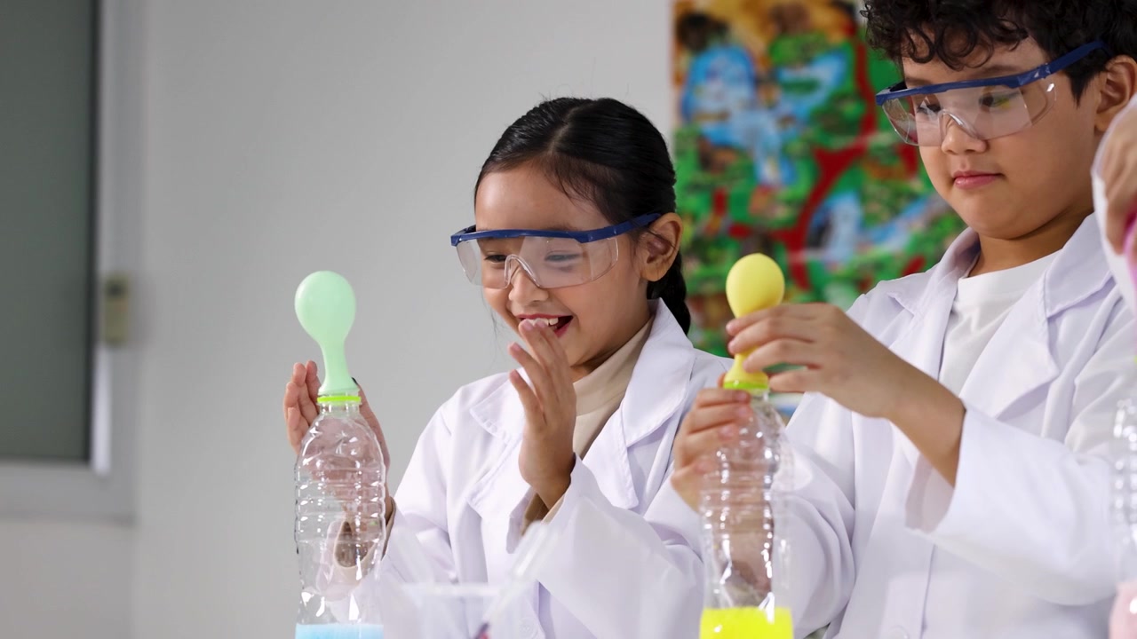 Siswa mengenakan jas lab melakukan percobaan reaksi kimia menggunakan botol plastik dan balon.