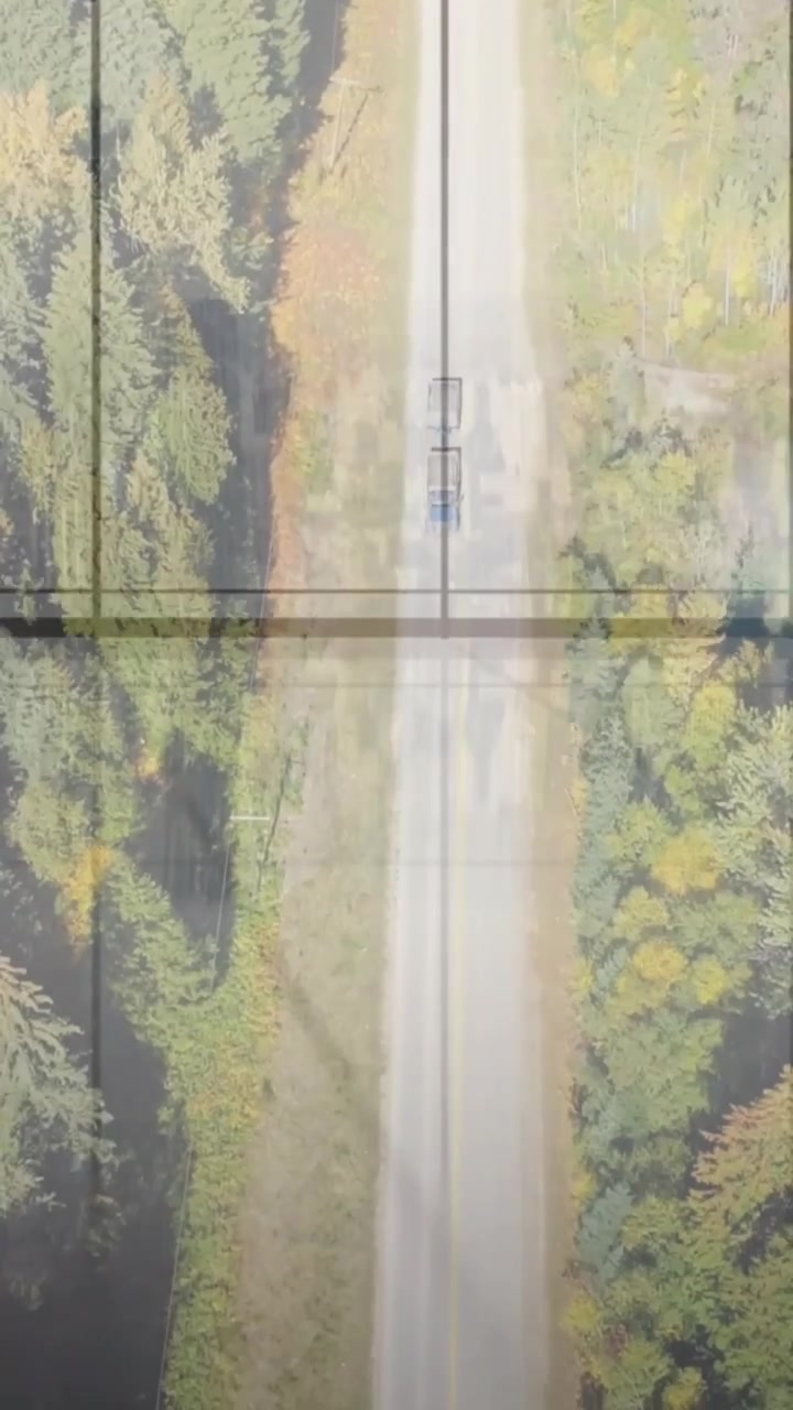 Video verticale: Ripresa aerea che mostra un primo camion che entra e poi un secondo, sollevando polvere sulla strada sotto una griglia.