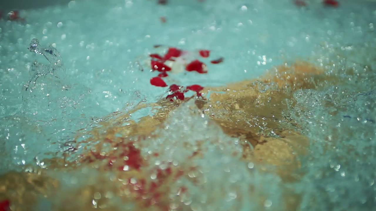 girl in a bikini in the jacuzzi. in rose petals and bubbles. slow motion.