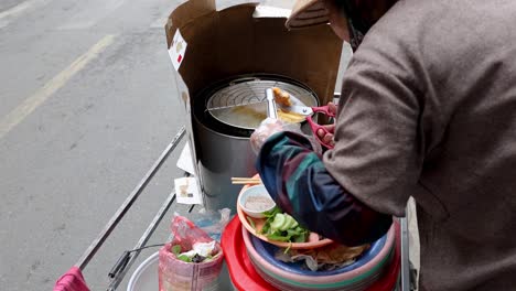 vendor cooking and assembling street food in hanoi