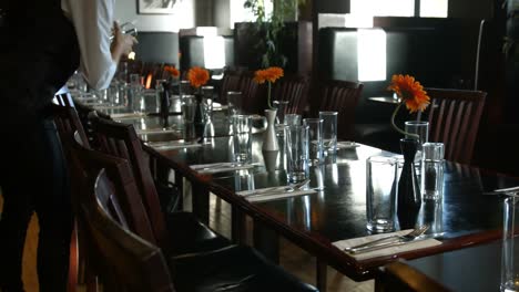 elegant waiter laying glasses on table