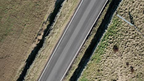 A-drone-rotation-shot-of-a-road-in-the-peak-district-with-a-car-passing-through-at-the-end-of-the-rotation