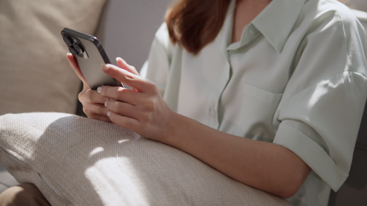 A person engages with their smartphone highlighting modern communication in a cozy setting.
