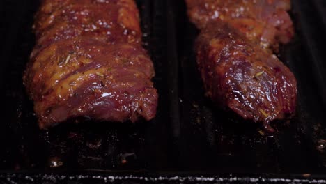 tilt down closeup, raw beef steaks with bubbling grease grill on cast iron