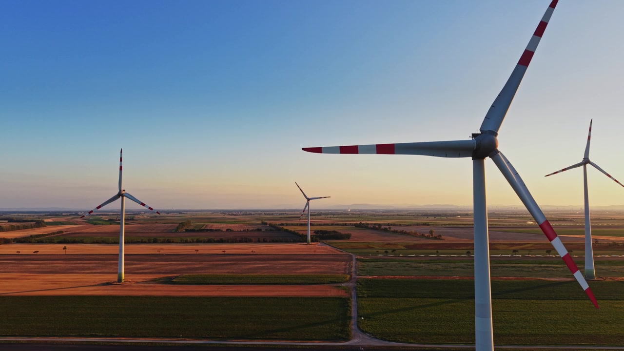 Wind turbines generate energy in a field during sunset