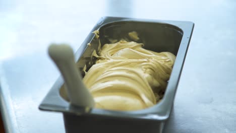 gelato in metal serving tray with spoon on table, closeup with soft focus