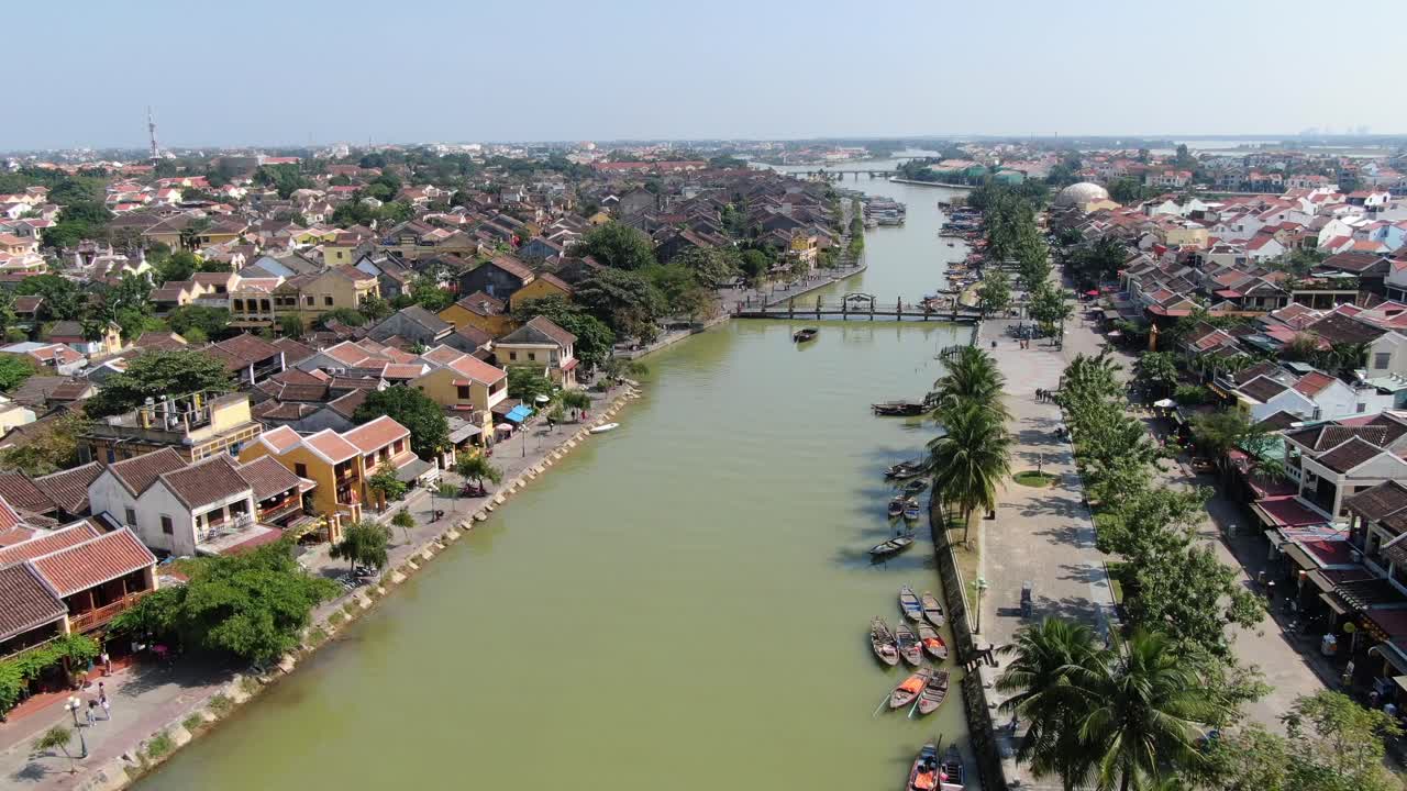 베트남에서 드론이 호이를 날아다니며 도시에서 갈색 강 운하, 작은 벽돌 집과 나무