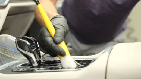 a car service worker wipes the instrument panel with a special brush. washing the car interior with a soft brush and foam. a car service worker wipes the instrument panel with a special brush