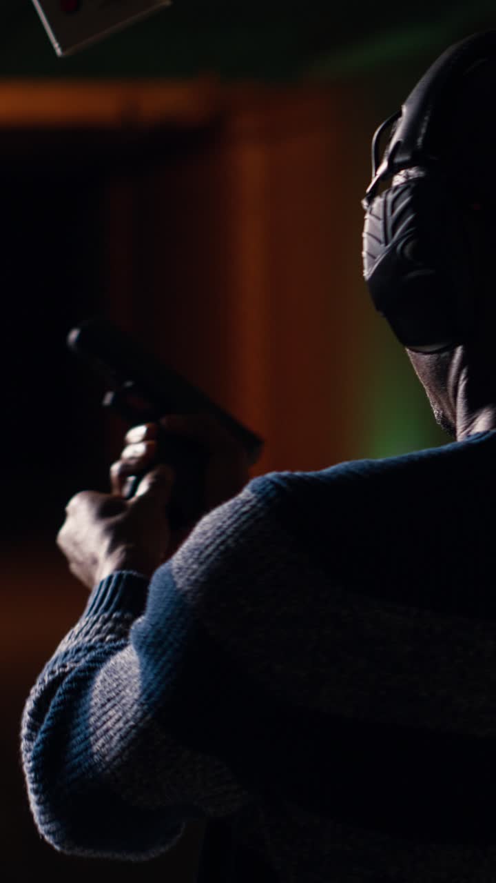 Vertical video Man reloading handgun in indoor shooting range next to friends firing at targets