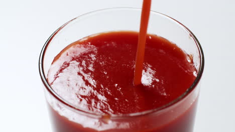 filling a tall glass up to its brim with a cold and fresh tomato juice