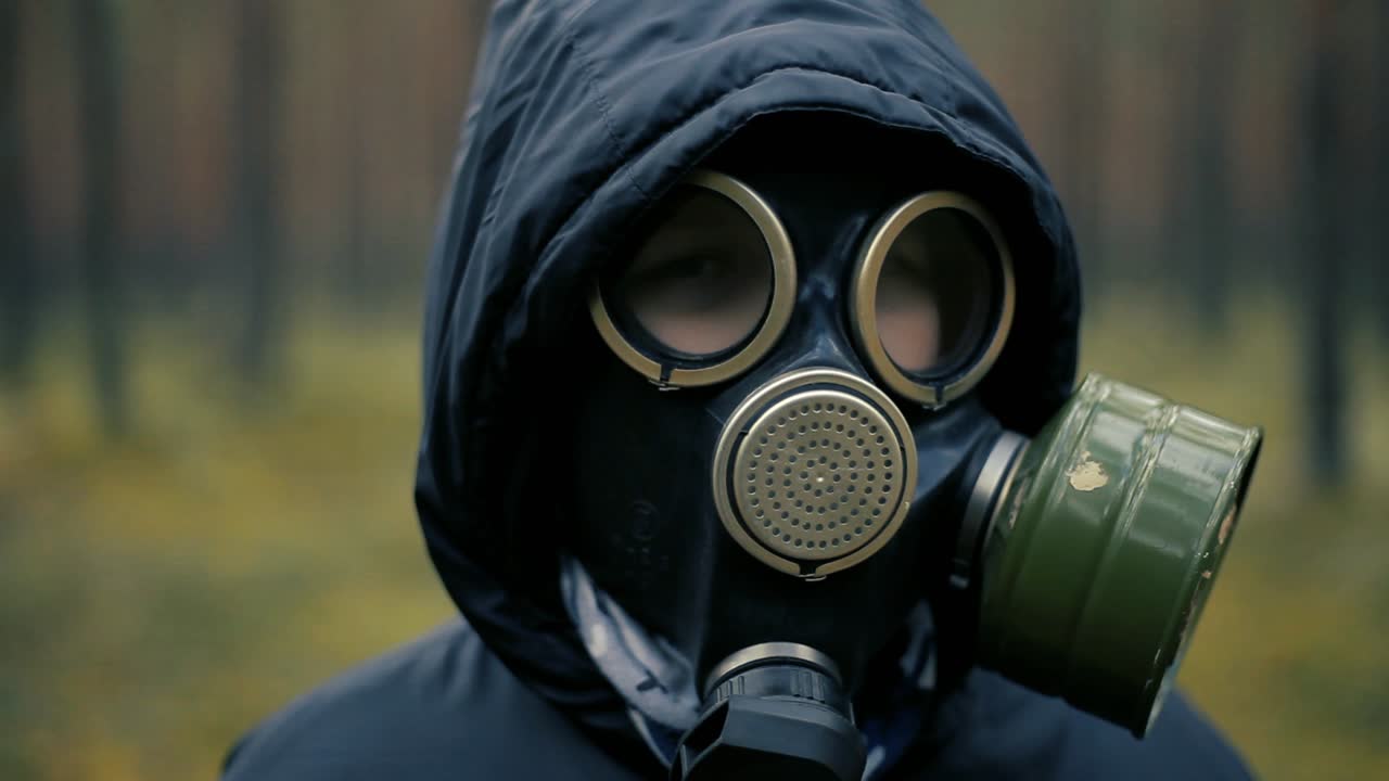 Child in pine forest with black gas mask on face