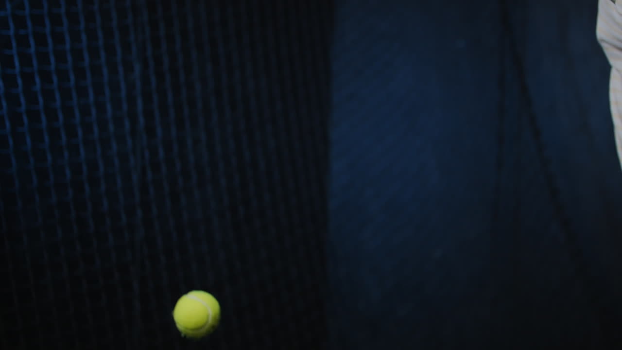 A player prepares for a padel serve, wearing a watch, indoors, with slow-motion detail