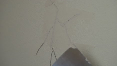 worker spreading and filling the cracks on wall with concrete putty using a putty knife scraper. - closeup