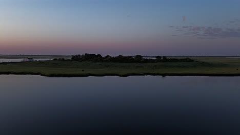 an aerial view of the salt marsh off freeport, new york on a cloudy day. the drone camera dolly in and slowly boom up over the waters and green marsh grass