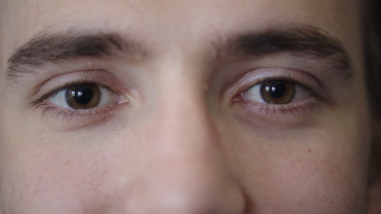 젊은 남자의 가까운 눈은 안경을 벗고 카메라를 보는 귀여운 백인 괴짜