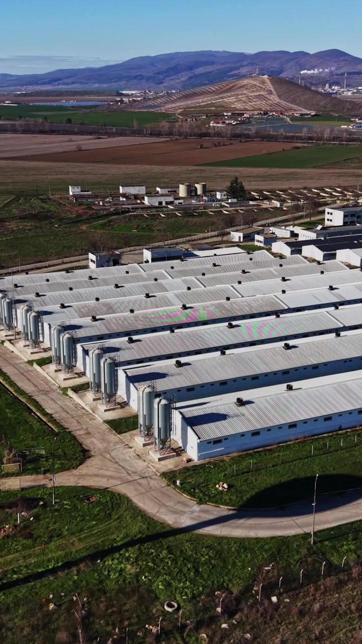 Sito industriale con campi verdi e montagne sullo sfondo