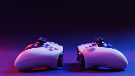 Video of close up of video game pad controllers with copy space on neon background