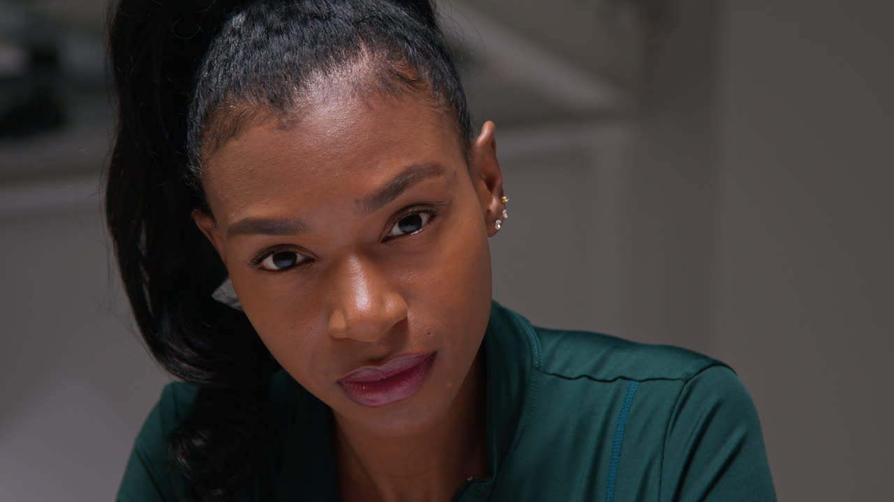 체육관에서 운동 훈련을 하고, 옷차림실에서 앉아서 집중하고, 집중된 표정으로 운동하는 여성 운동선수.