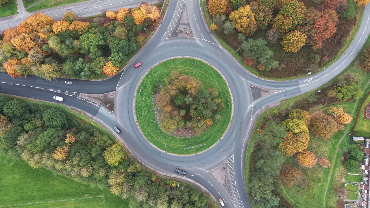 Static overhead drone shot of cars driving on a roundabout in autumn