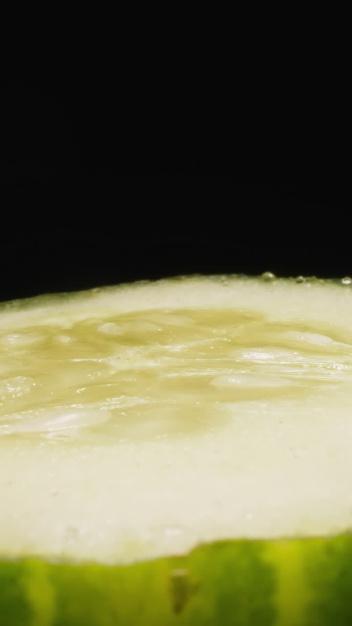 Cut sluggish cucumber with seeds turning on black background. Natural green vegetable used for vegetarian salads and delicious dishes macro