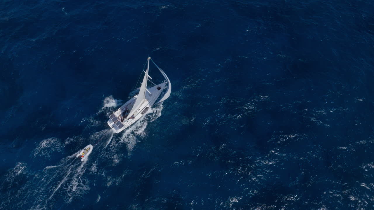Aerial view of luxury yacht sailing at full speed over tropical azure open ocean