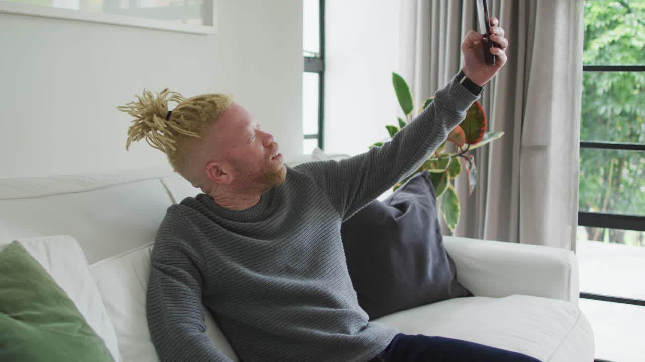 Uomo afroamericano albino con i dreadlock che usa lo smartphone.
