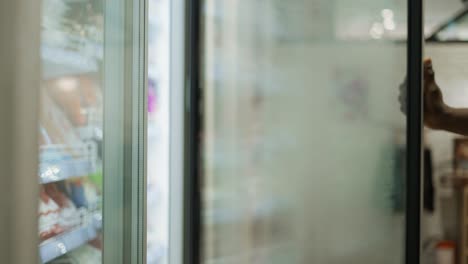 a shopper selects food in the fridge of a grocery store