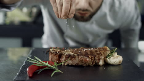 Koch-Salzt-Fleisch-Am-Grill.-Nahaufnahme-Eines-Mannes,-Der-Salzsteak-In-Zeitlupe-überreicht.