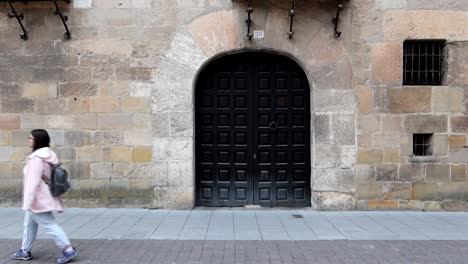 caucasian woman walking past palacio de los berdugo in burgos, spain