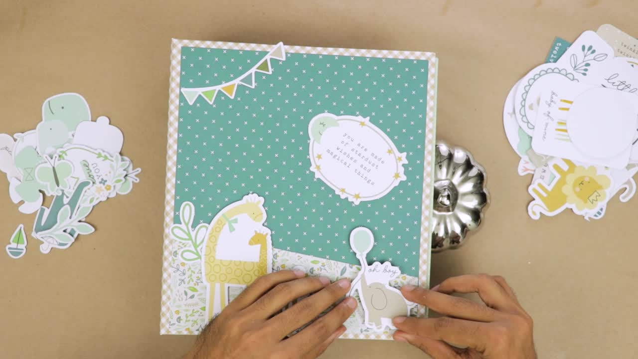 Creating cute scrapbook baby album cover with decorative paper cutouts and embellishments