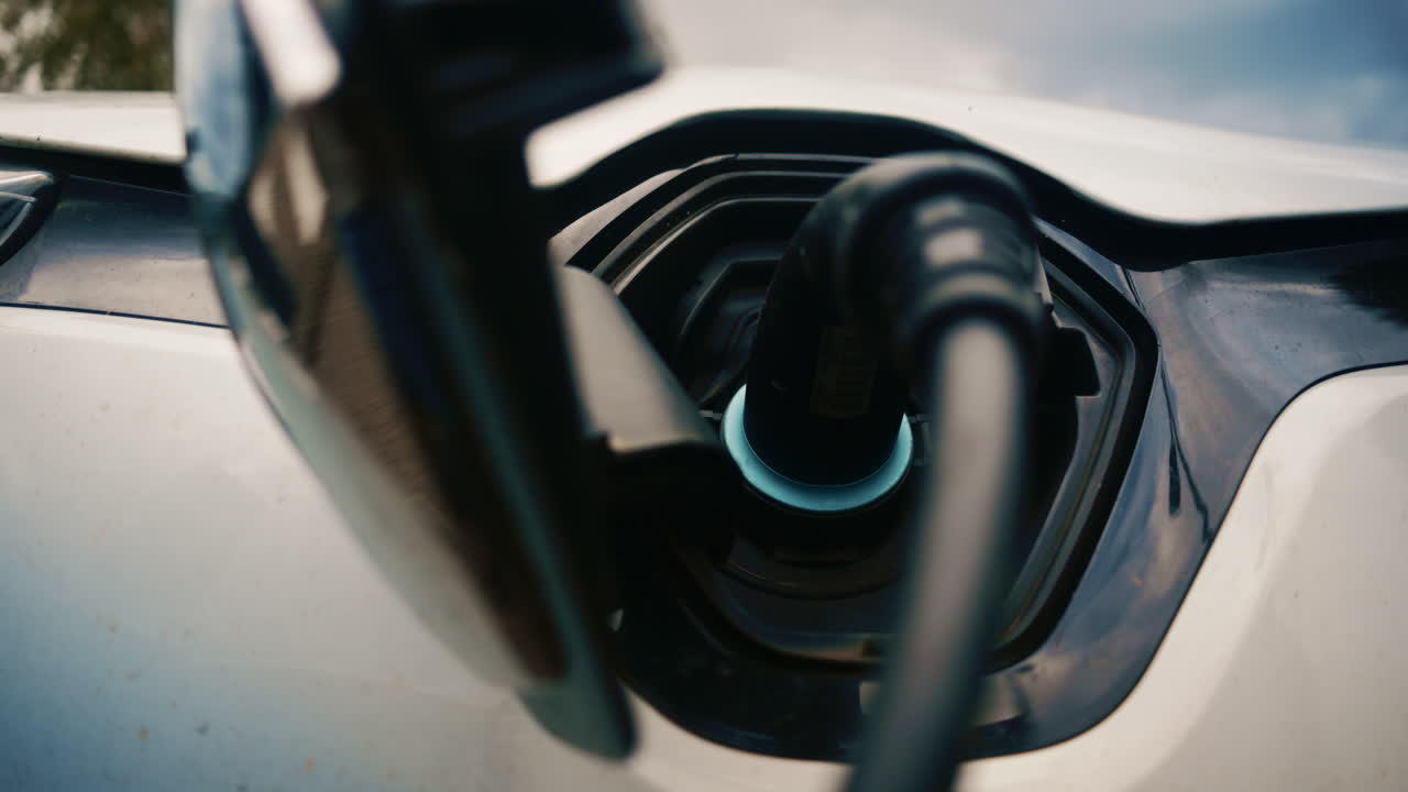 Close up of a white electric vehicle plugged into a charging port