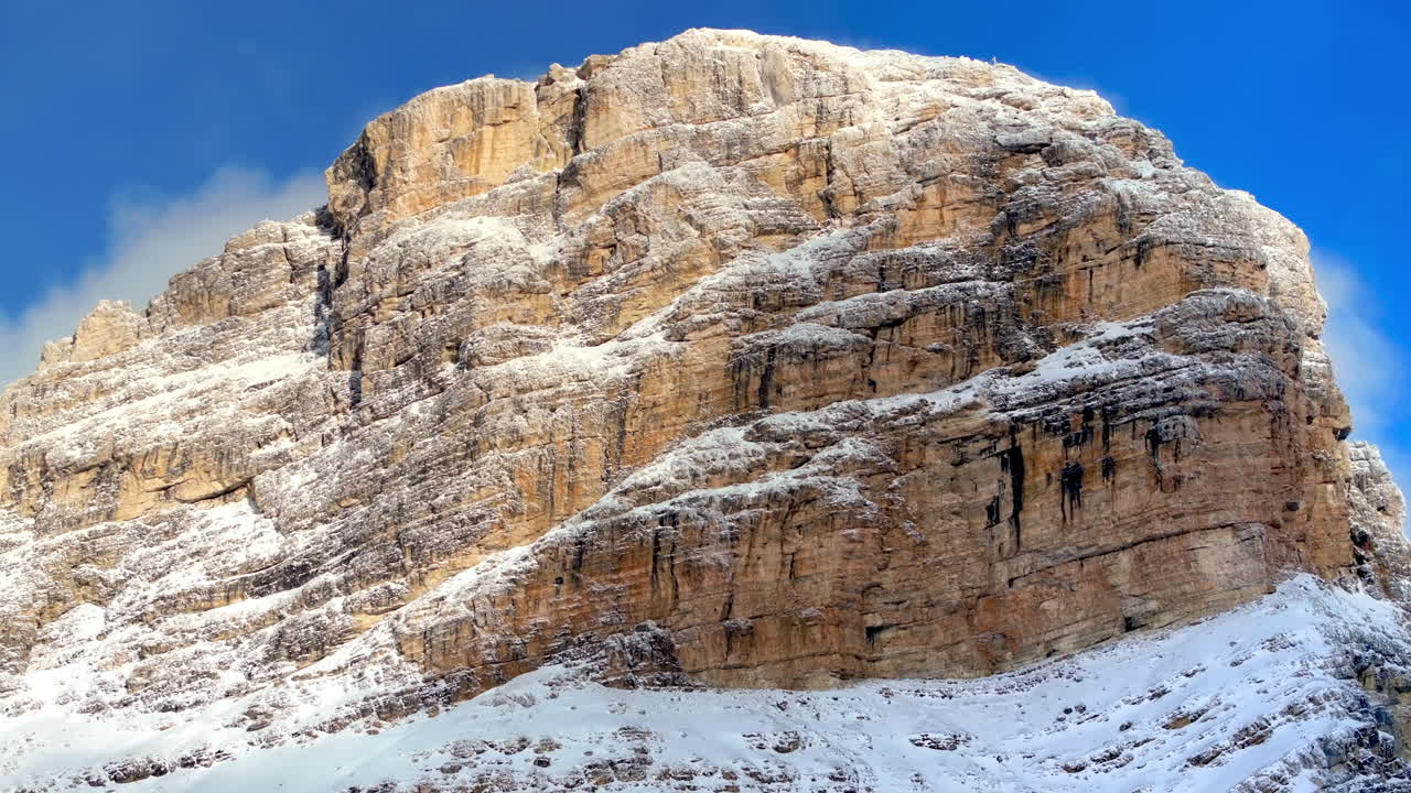 Aerial drone view of snow on the Sassongher mountain in the Dolomites, Italy with the blue sky on the background
