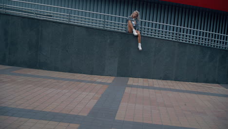 Sitzende-Frau,-Stadthintergrund,-Der-Für-Ein-Foto-In-Der-Leeren-Straße-Der-Innenstadt-Posiert.