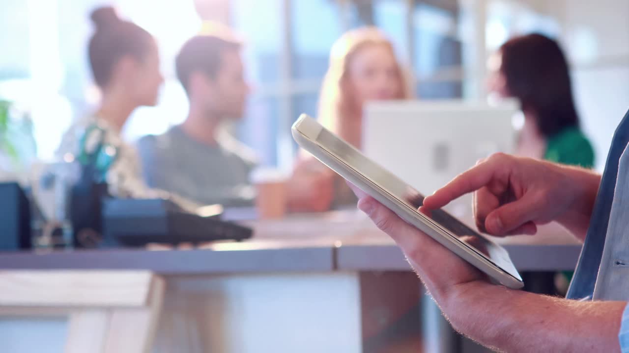 hombre de negocios usando una tableta con sus colegas detrás de él