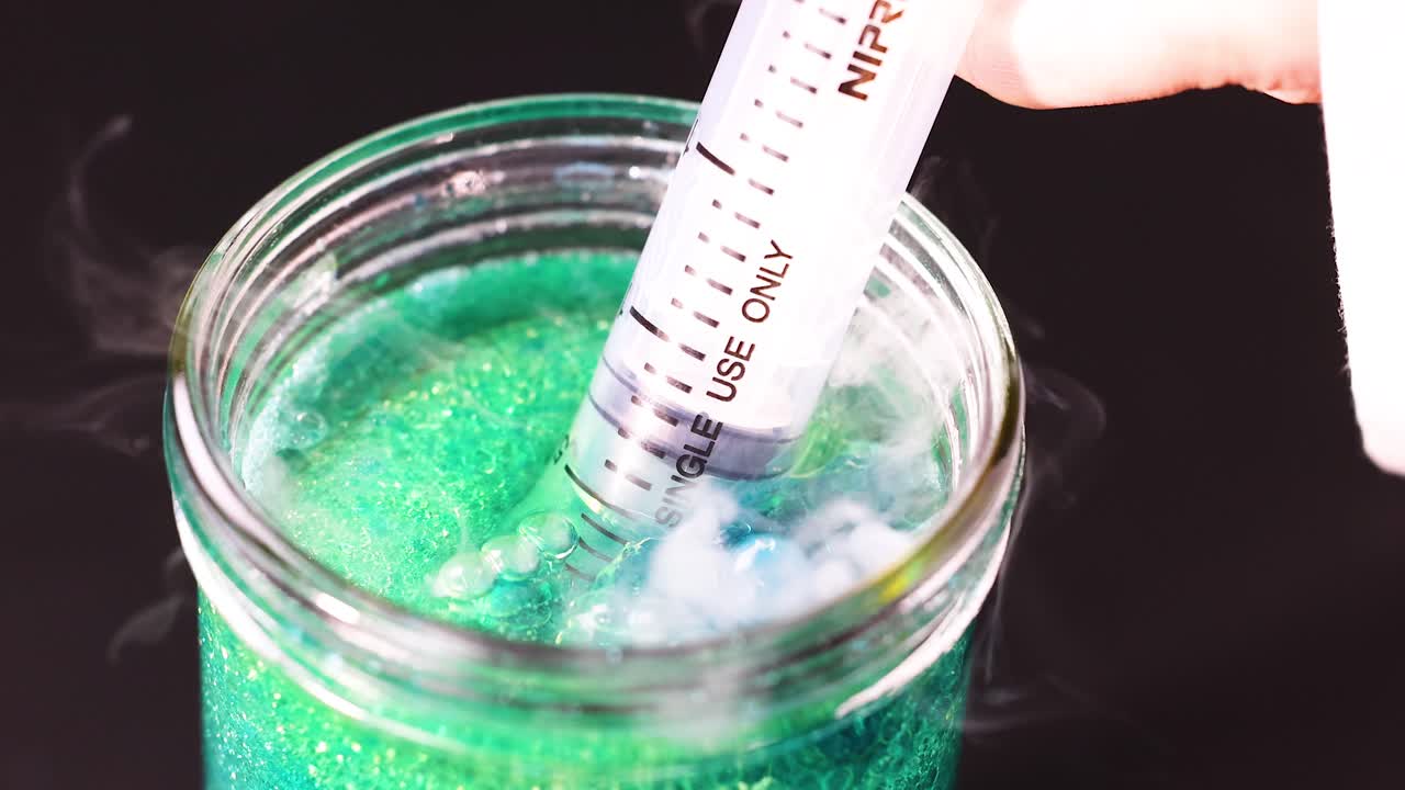 주사기가 항아리에 있는 다채로운 액체와 상호 작용합니다.