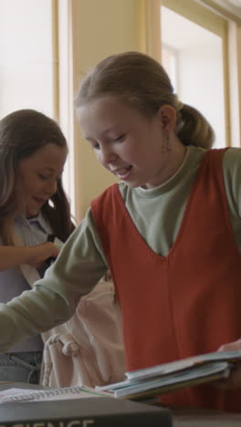 elementary school girls studying and interacting with books in a classroom